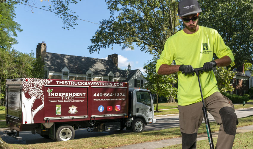 An Independent Tree employee using PHC truck injections to protect a home from pests and diseases as part of an IPM program