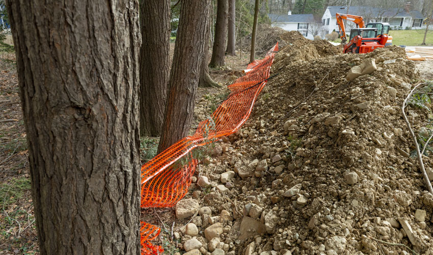 Dirt from a construction project in Ohio near trees and a protective plastic fence