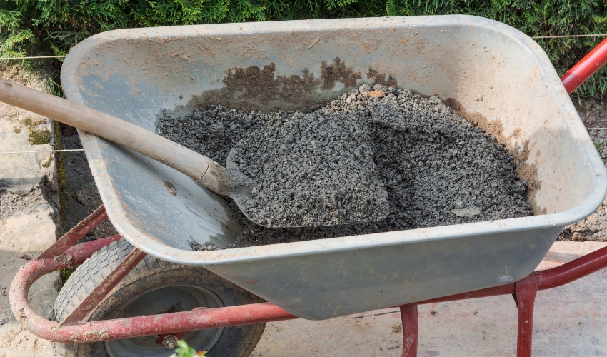 Wheelbarrow filled with wet cement and a shovel, representing outdated practices for filling tree cavities.